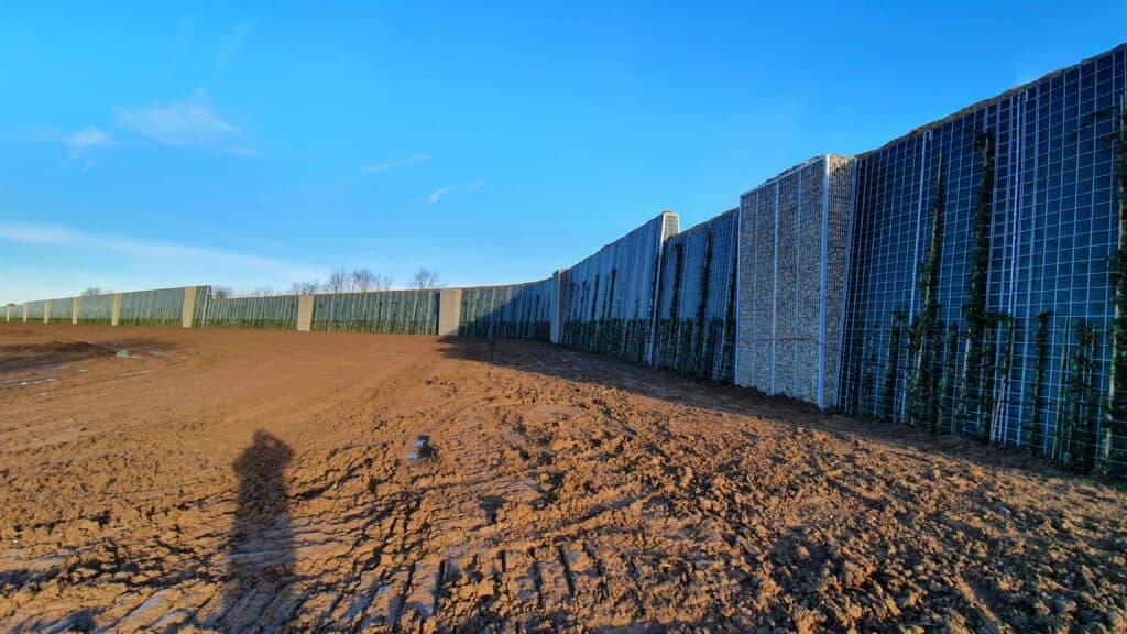 Laermschutzwand-entlang-einer-unbefestigten-Flaeche