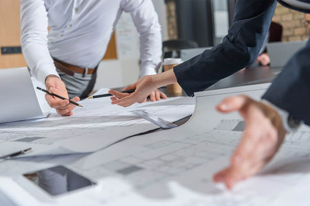 Personen-besprechen-Bauplaene-an-einem-Tisch-in-einem-Buero