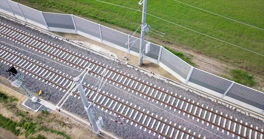 RAU AL Luftaufnahme einer Schallschutzwand entlang von Bahngleisen in ländlicher Umgebung